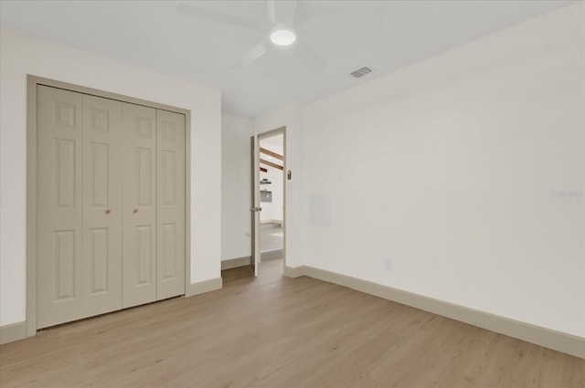 unfurnished bedroom with light wood-type flooring, a closet, visible vents, and baseboards