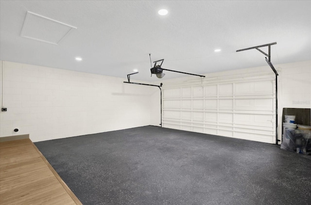 garage with recessed lighting, concrete block wall, and a garage door opener