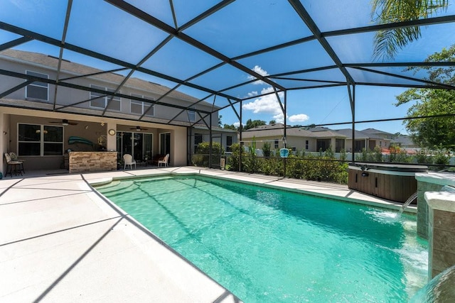 pool featuring glass enclosure, a hot tub, a patio area, and a ceiling fan