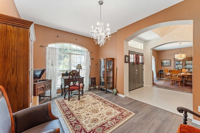 foyer with dark wood-style floors, baseboards, arched walkways, and an inviting chandelier