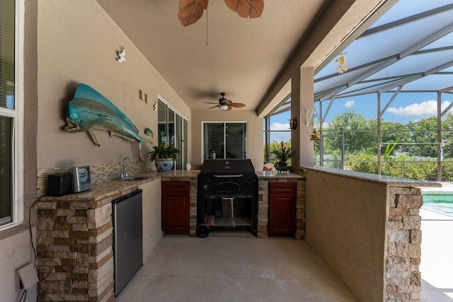 view of patio / terrace with glass enclosure, area for grilling, a sink, a ceiling fan, and a grill