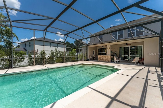 pool with glass enclosure, a ceiling fan, and a patio