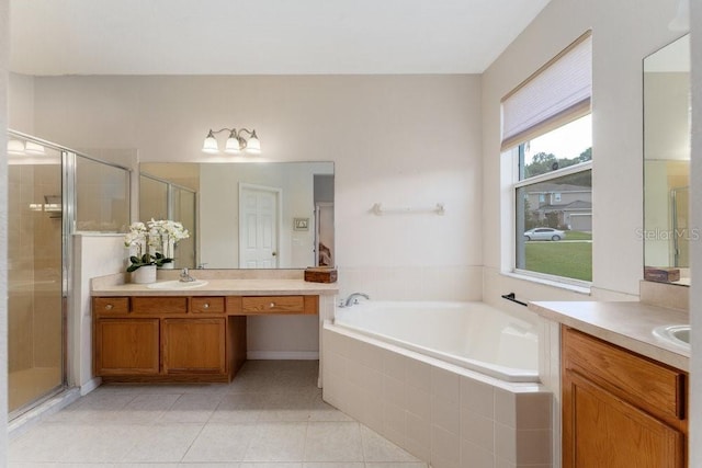 full bath featuring a garden tub, tile patterned flooring, two vanities, a sink, and a stall shower