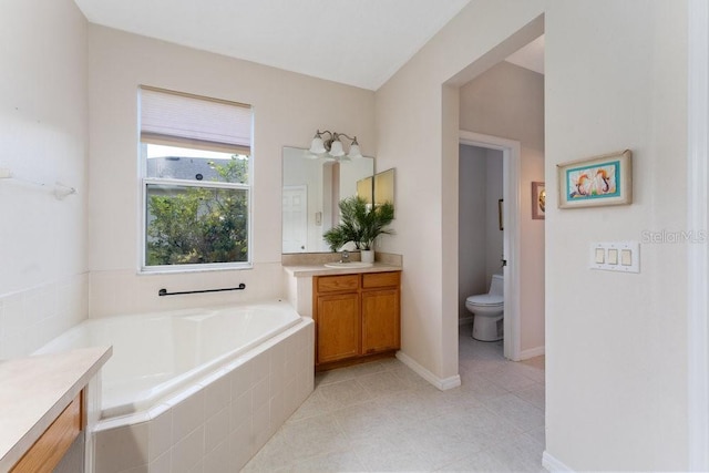 full bathroom featuring baseboards, a garden tub, vanity, and toilet