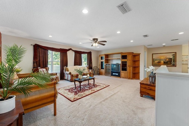 living room with recessed lighting, visible vents, light carpet, and a textured ceiling