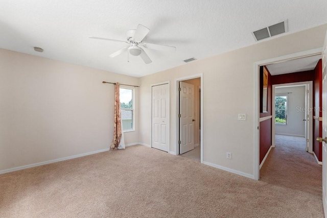 unfurnished bedroom featuring light carpet, a closet, visible vents, and baseboards