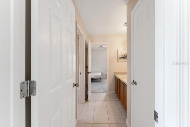 bathroom with baseboards, visible vents, tile patterned flooring, a textured ceiling, and vanity