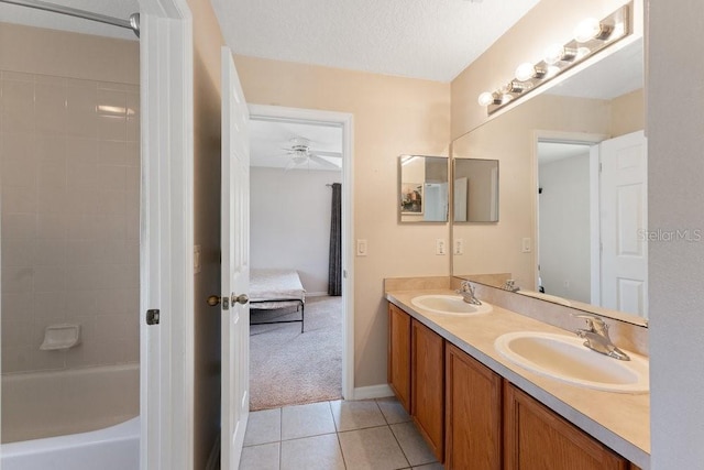 ensuite bathroom with a textured ceiling, double vanity, a sink, and tile patterned floors