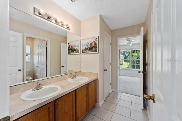 full bathroom featuring toilet, double vanity, a sink, and tile patterned floors