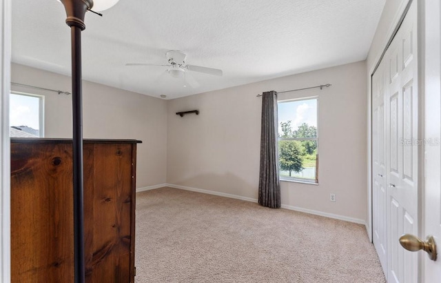 bedroom featuring a textured ceiling, baseboards, and light colored carpet