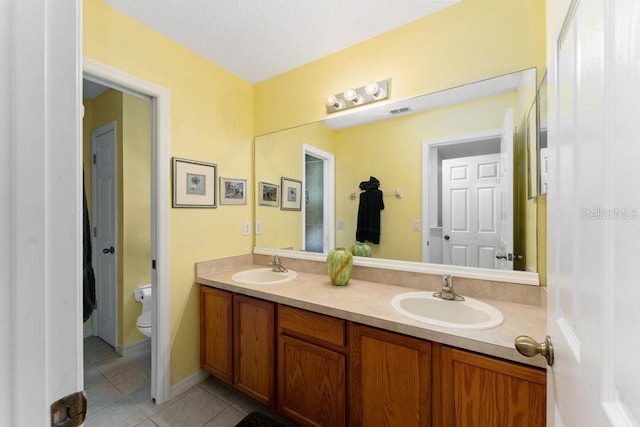 bathroom featuring double vanity, tile patterned flooring, a sink, and toilet