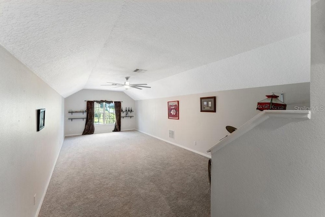 bonus room with ceiling fan, a textured ceiling, visible vents, vaulted ceiling, and carpet