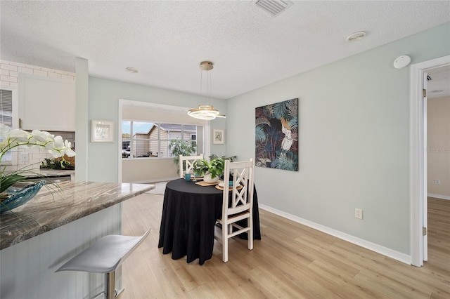 dining area featuring a textured ceiling and light wood-type flooring