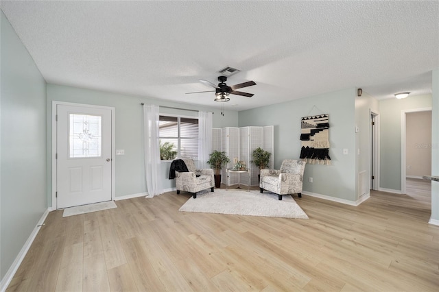 living area featuring ceiling fan, a textured ceiling, and light hardwood / wood-style floors