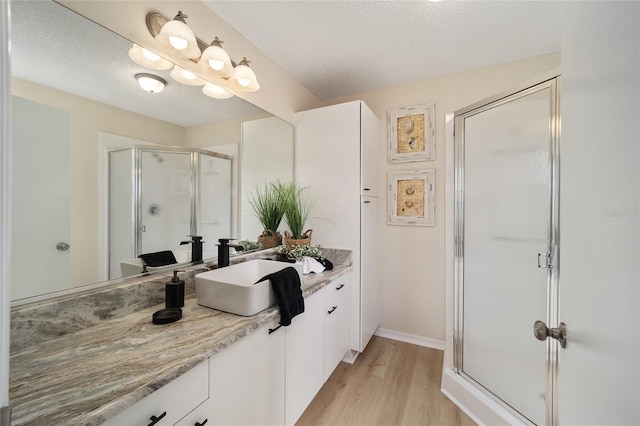 bathroom featuring vanity, hardwood / wood-style flooring, a textured ceiling, and walk in shower