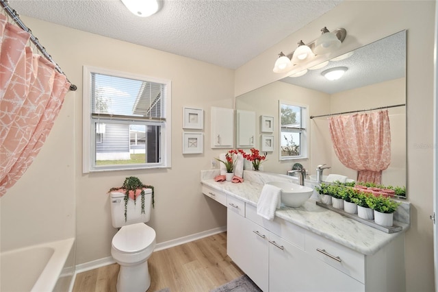 full bathroom featuring hardwood / wood-style flooring, vanity, toilet, and a textured ceiling