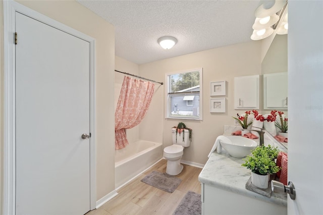 full bathroom featuring shower / tub combo with curtain, toilet, a textured ceiling, vanity, and hardwood / wood-style floors