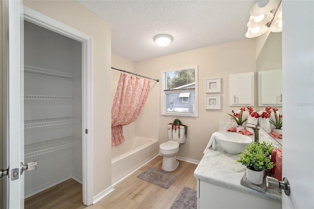 full bathroom featuring hardwood / wood-style flooring, vanity, a textured ceiling, and toilet