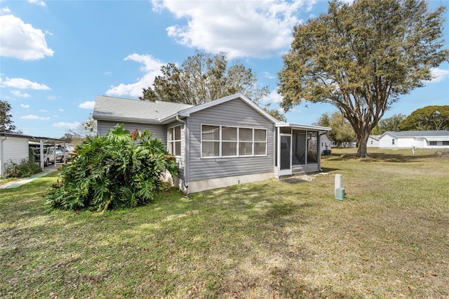 back of house featuring a sunroom and a lawn