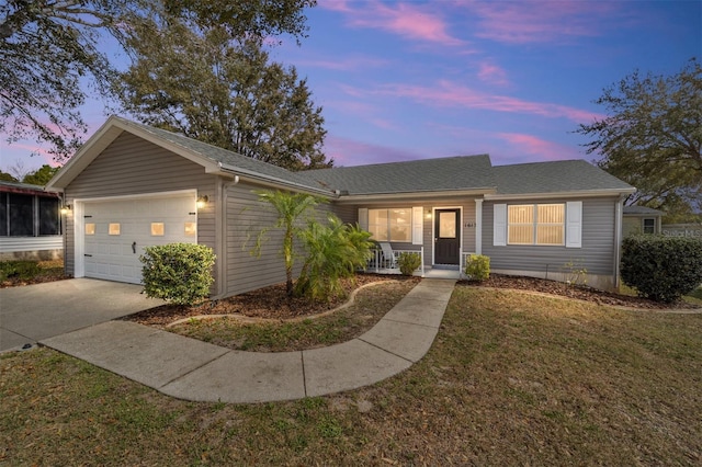 ranch-style home with a garage, covered porch, and a lawn