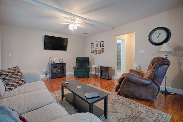 living room featuring wood-type flooring, ceiling fan, and a textured ceiling