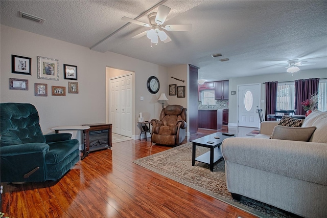 living room featuring ceiling fan, hardwood / wood-style floors, and a textured ceiling