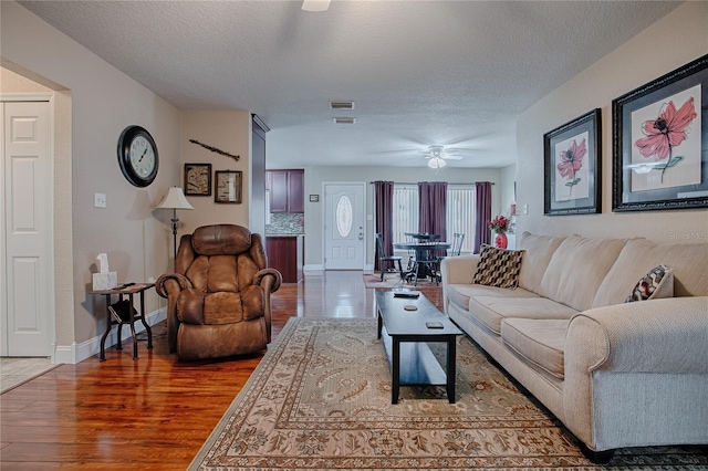 living room with ceiling fan, hardwood / wood-style floors, and a textured ceiling