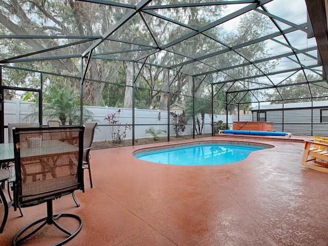 view of swimming pool with a hot tub, glass enclosure, and a patio area