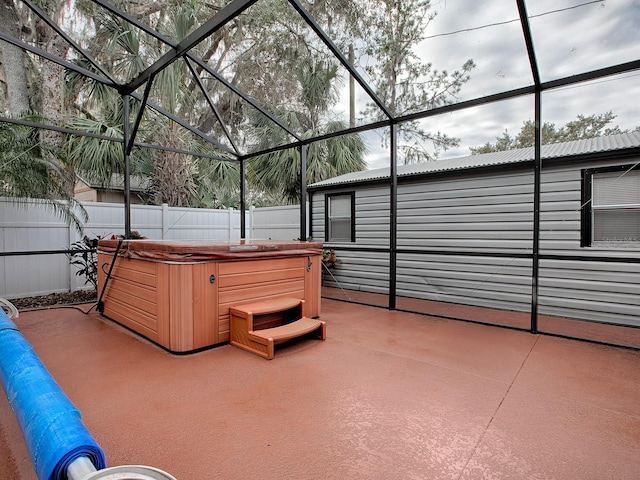 view of patio / terrace featuring a hot tub and glass enclosure