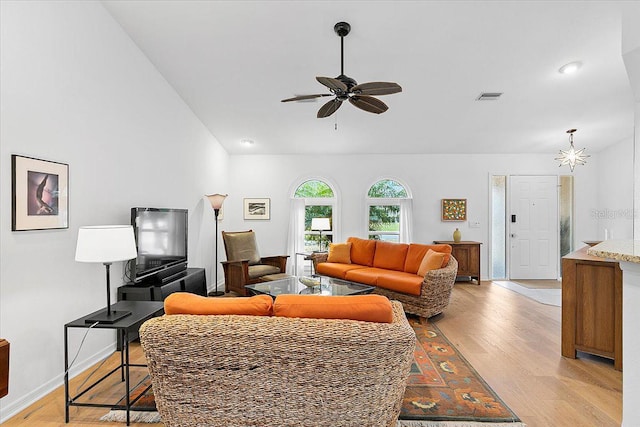 living room with lofted ceiling, ceiling fan with notable chandelier, and light hardwood / wood-style floors