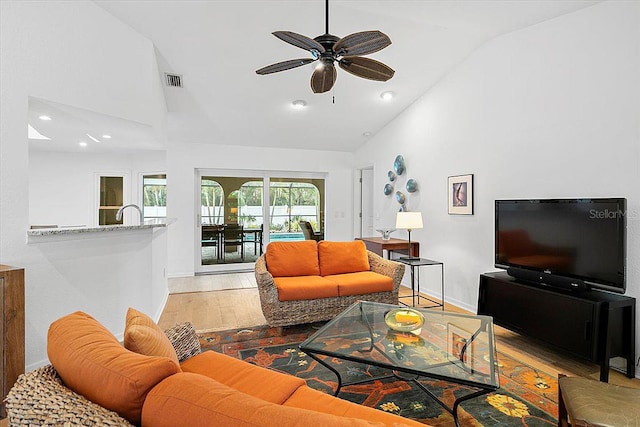 living room with light hardwood / wood-style flooring, high vaulted ceiling, and ceiling fan