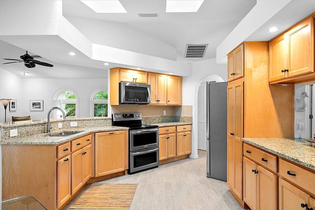 kitchen featuring sink, appliances with stainless steel finishes, light stone counters, decorative backsplash, and kitchen peninsula