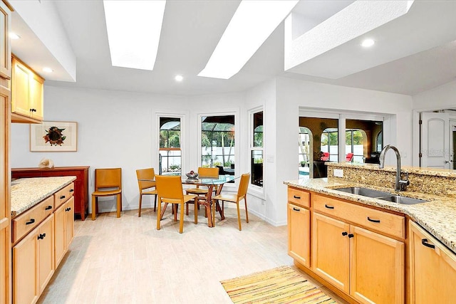 kitchen featuring light stone counters, plenty of natural light, sink, and light brown cabinets