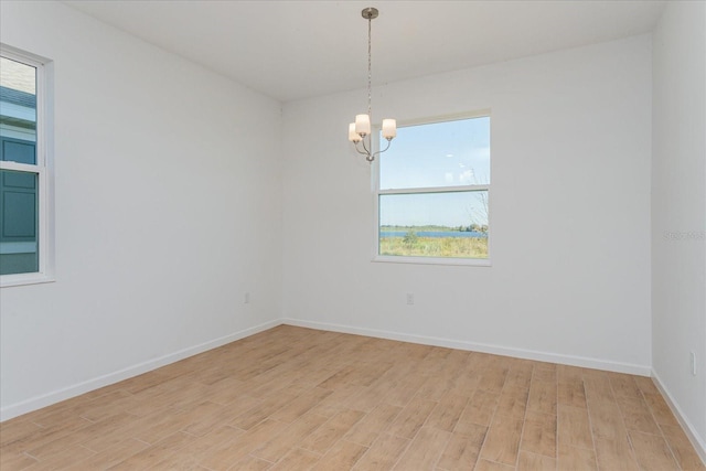 empty room with a notable chandelier and light hardwood / wood-style flooring