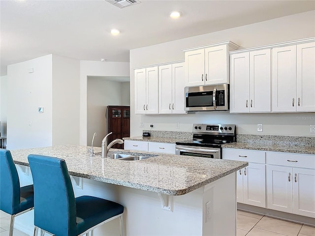 kitchen with sink, white cabinetry, stainless steel appliances, a kitchen breakfast bar, and an island with sink