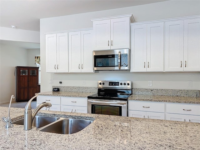 kitchen with light stone counters, sink, stainless steel appliances, and white cabinets