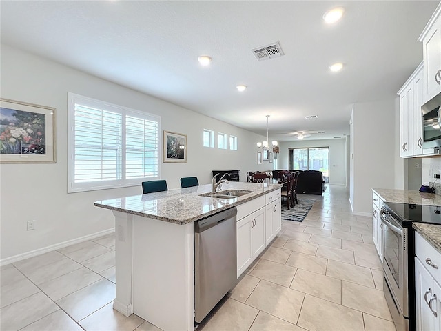 kitchen featuring white cabinetry, sink, a kitchen island with sink, stainless steel appliances, and light stone countertops