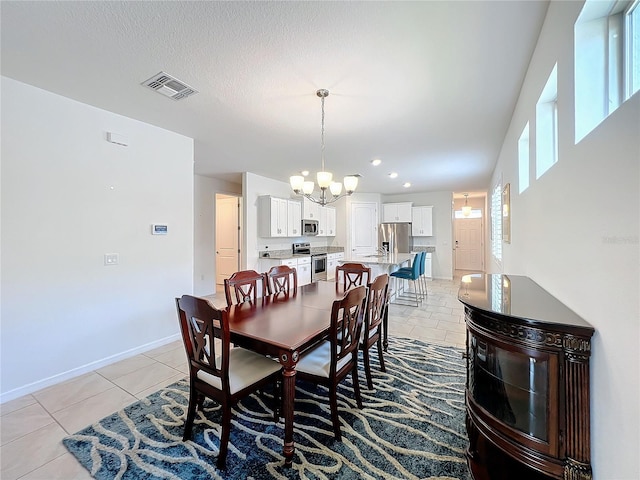 tiled dining area featuring a textured ceiling and an inviting chandelier