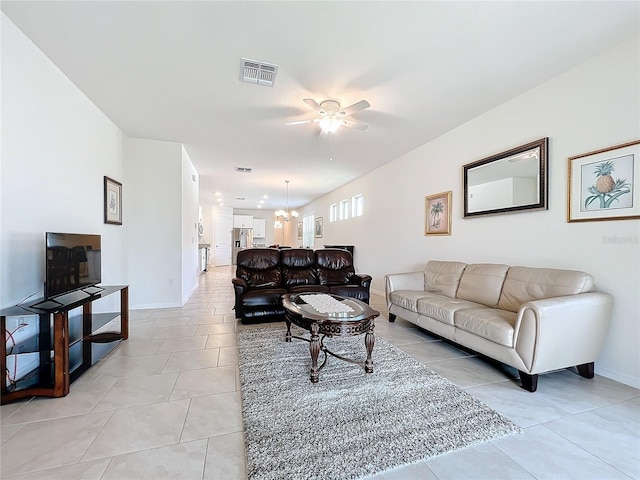 tiled living room featuring ceiling fan with notable chandelier