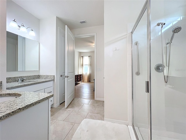 bathroom with a shower with door, vanity, and tile patterned floors