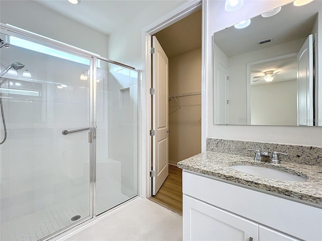 bathroom with vanity, a shower with shower door, and ceiling fan