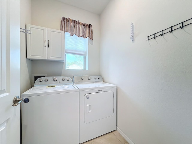 clothes washing area featuring light tile patterned flooring, cabinets, and washing machine and clothes dryer