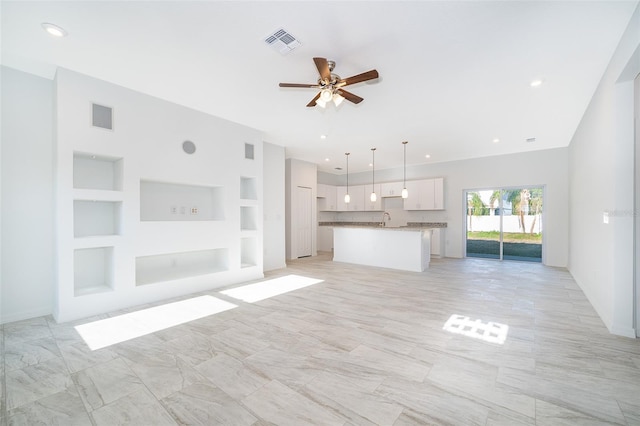 unfurnished living room with sink, built in shelves, and ceiling fan