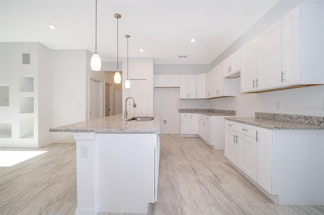 kitchen with sink, an island with sink, and white cabinets