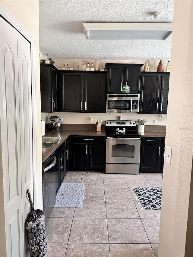 kitchen featuring stainless steel appliances, sink, a textured ceiling, and light tile patterned floors