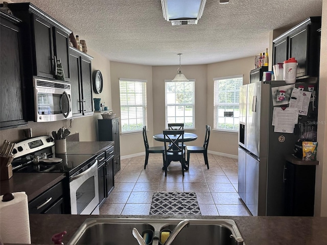 kitchen featuring stainless steel appliances, decorative light fixtures, light tile patterned floors, and a wealth of natural light