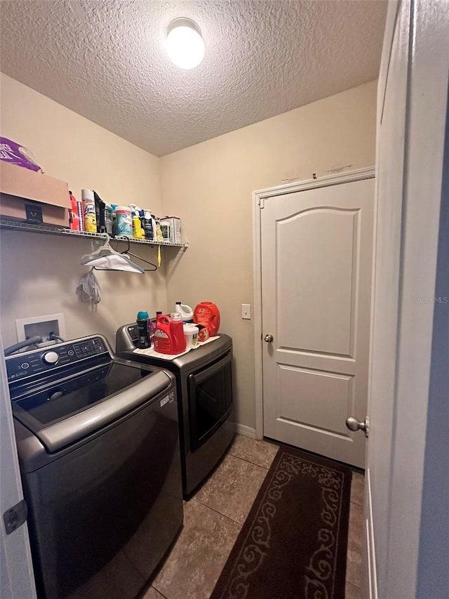 laundry area with light tile patterned floors, washer and clothes dryer, and a textured ceiling