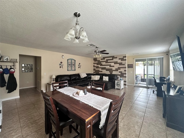 tiled dining area featuring ceiling fan with notable chandelier and a textured ceiling