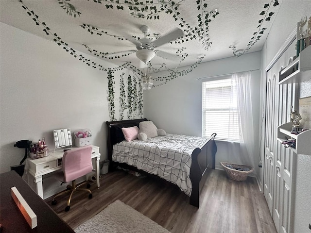 bedroom with dark wood-type flooring, rail lighting, ceiling fan, a textured ceiling, and a closet