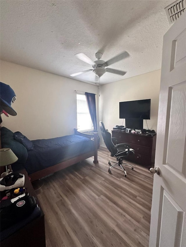 bedroom with wood-type flooring, a textured ceiling, and ceiling fan